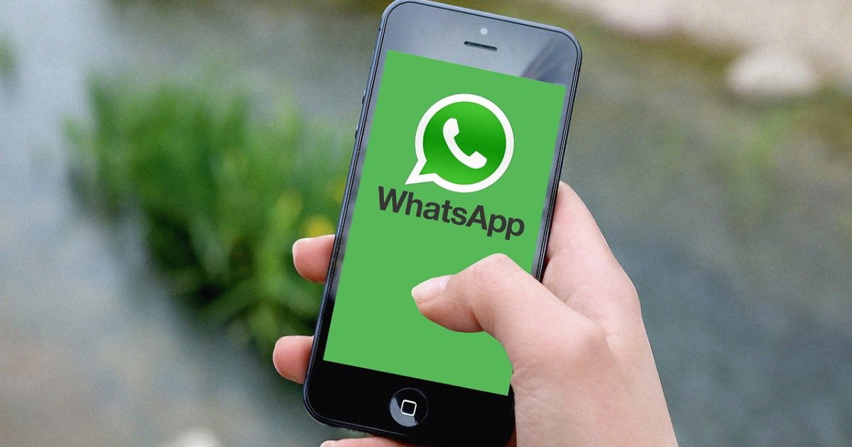 香蕉社区 App 主视觉：深色桌面上一部竖屏手机亮着目录页，暖黄台灯光斜落在木质桌面上，背景书脊虚化
